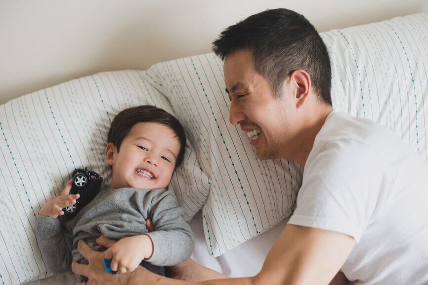 father tickling his laughing baby son