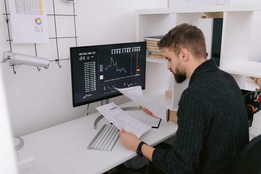 Person reading papers in front of desktop computer